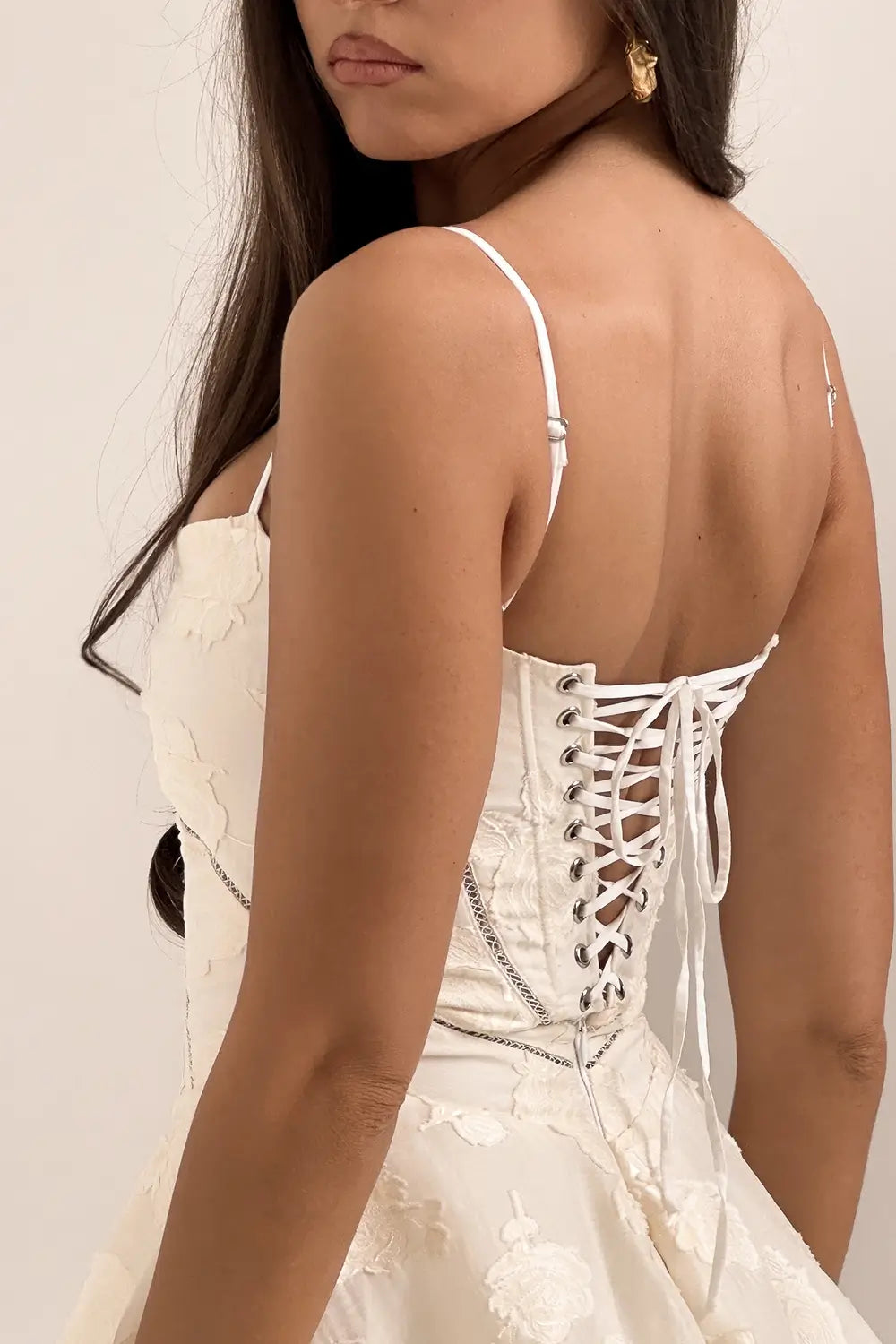 Vestido corto blanco elegante con encaje floral, escote corazón, corset ajustable y espalda descubierta. Modelo Serenita de Veliara, ideal para fiestas, cenas románticas, cumpleaños, eventos nocturnos y escapadas. Falda mini fluida con movimiento natural.