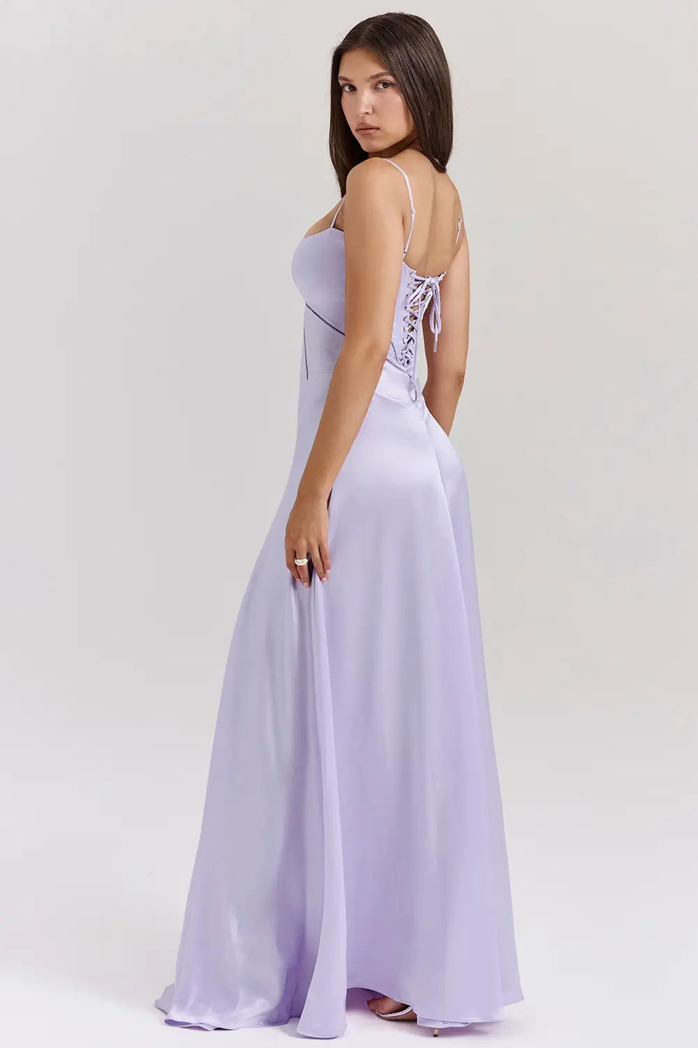 Vestido largo lila elegante para mujer con espalda descubierta y detalle de encaje delicado, ideal para bodas, fiestas formales, cenas especiales y eventos de noche. El modelo Mavie de Veliara está confeccionado en una tela de caída fluida que se adapta al cuerpo con suavidad, realzando la silueta sin apretar. Su escote recto y diseño sin tirantes ofrecen un look sofisticado y sensual, mientras que el encaje en la espalda añade un toque de romanticismo moderno.