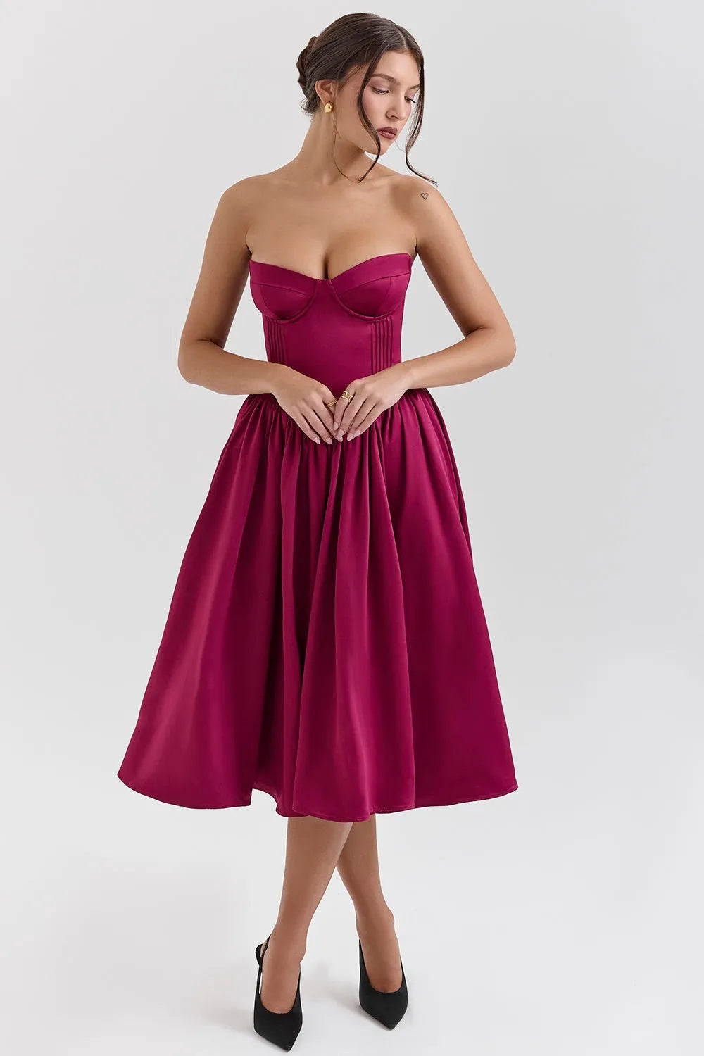 Modelo usando vestido midi juvenil color vino con corset estructurado y falda tipo bailarina. Ideal para fiestas, bodas o cenas elegantes.